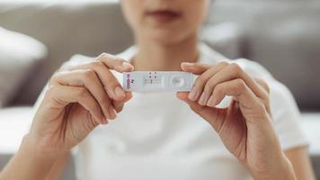 autoprueba de mujer para el kit de prueba casera covid-19. mujer asiática que muestra el resultado kit de prueba casera de antígeno rápido de coronavirus, prueba de hisopo nasal de coronavirus para infección. foto