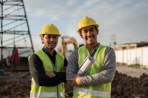 hombres ingenieros que trabajan en el sitio de construcción. hombres trabajadores asiáticos sonriendo y cruzados de brazos en el sitio de construcción. foto