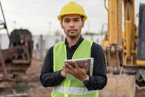 hombre ingeniero trabajando en el sitio de construcción. hombre joven trabajador que trabaja en el sitio de construcción. concepto de construcción e ingeniería civil. foto