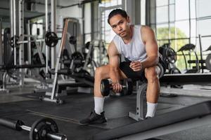 ejercicios de hombre asiático en fitness. hombre en forma haciendo ejercicios de curl de bíceps en el gimnasio. foto