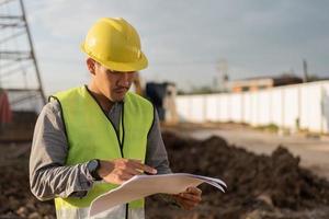 hombre ingeniero trabajando en el sitio de construcción. hombre joven trabajador que trabaja en el sitio de construcción. concepto de construcción e ingeniería civil. foto