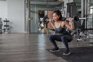 ejercicio de mujer asiática en fitness. joven mujer sana en ropa deportiva haciendo ejercicio de piernas en fitness. foto