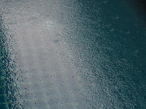 gotas de lluvia que caen agua azul en el fondo de la piscina ondulaciones en la textura de la superficie, resumen de bokeh brillante foto