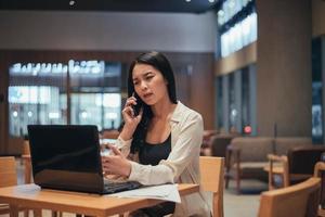 mujer seria que trabaja en la computadora portátil a altas horas de la noche. empresaria asiática trabajando duro y horas extras en el cargo. foto