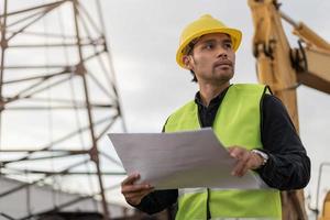 hombre ingeniero trabajando en el sitio de construcción. hombre joven trabajador que trabaja en el sitio de construcción. concepto de construcción e ingeniería civil. foto