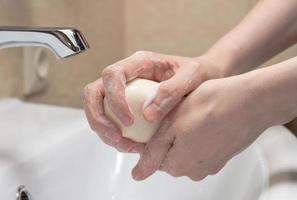 higiene. limpieza de manos. lavarse las manos con jabón. mano de mujer con jabón blanco y espuma. protégete de la pandemia del coronavirus covid-19 foto