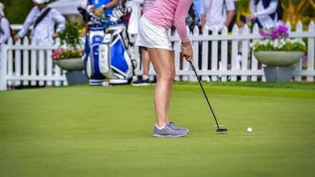 golfista empujando la pelota de golf blanca al hoyo en el campo de golf en el juego de competencia de golf, rayos de luz solar y fondo borroso foto