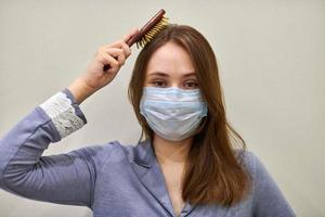 mujer con mascarilla protectora peinándose, de cerca. foto