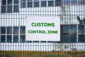 Customs control zone sign on metal fence, border symbol photo