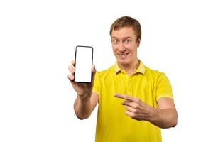 Smiling young guy with smartphone in hand isolated on white, phone mockup, mobile app advertisement photo