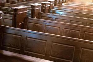 Cathedral benches. Rows of pews in christian church. Heavy solid uncomfortable wooden seats. photo