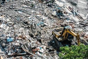 Construction working. The destroyed building is dismantled by a yellow excavator. Dismantling of the old building and start the construction of new buildings. photo