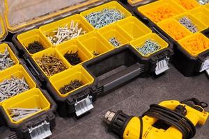 Storage boxes on floor with screws, nuts, bolts, nails and other small tools for handyman, close up photo