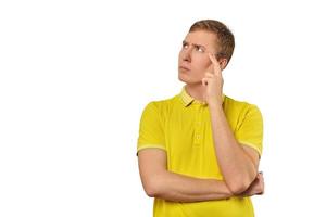 Thoughtful guy in yellow T-shirt looking to left, white background, philosophical reflection photo