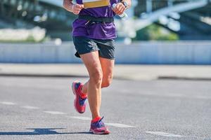 mujer corriendo. mujer fitness trotar en ropa deportiva en la carretera de la ciudad. estilo de vida saludable, pasatiempo deportivo. entrenamiento en la calle, correr al aire libre foto