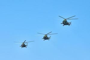 Three military helicopters flying in blue sky performing demonstration flight, air show, copy space photo