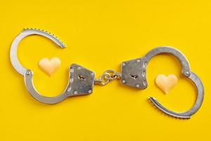 Opened handcuffs on yellow background. photo