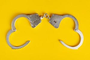 Opened handcuffs on yellow background. photo