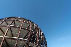 Unfinished sphere shape building, copy space. Construction of futuristic shopping mall or museum. Building constructed of concrete and reinforcement. photo