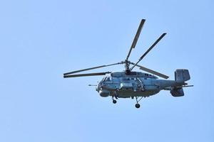 Navy helicopter flying against blue sky, copy space. One military warfare helicopter, side view photo