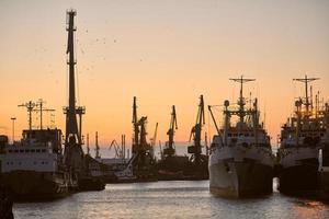 Ships in sea port on sunset background photo