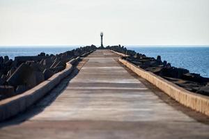 Empty long concrete pier with breakwaters and signal lighthouse in Europe, sea port, copy space photo