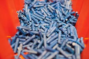 Plastic blue dowels on red background, wall plugs for fixation and installation, close up, top view photo