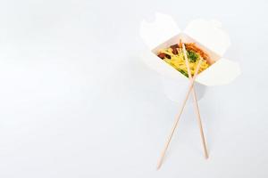 Rice wok in box and wooden chopsticks isolated on white background, Asian food delivery, copy space photo