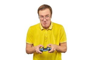 Geek gamer in glasses and yellow T-shirt with gamepad, excited video game player isolated on white photo