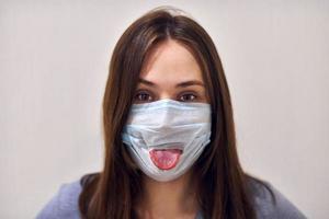 Funny girl wearing surgical mask and showing her tongue. photo