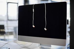 Earphones and computer monitor at workplace. Working with sound or listening to music at work. Listening to business phone conversations photo