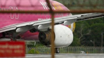 phuket, tailândia 5 de dezembro de 2016 - vista traseira de uma aeronave nok air boeing 737 com libré de bico de pássaro no nariz pronto para decolar do aeroporto de phuket. ver através da cerca video
