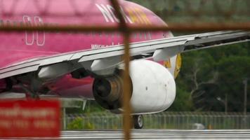 phuket, thailand 5 december 2016 - achteraanzicht van een nok air boeing 737-vliegtuig met een vogelbekkleurstelling op de neus, klaar om op te stijgen vanaf de luchthaven van phuket. uitzicht door het hek video