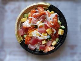 Direct above view of Kaisen don, seafood covered rice, topping with mixed raw fish, Japanese Steamed Rice, Salmon, Maguro and Tamago, salmon roe, squid, isolated on blur background photo