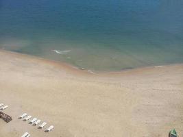 vista de gran ángulo de la playa de arena a orillas del mar con asientos blancos foto