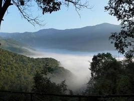 paisaje de la montaña cubierta de niebla por la mañana con rayos de sol calientes para papel tapiz de fondo foto