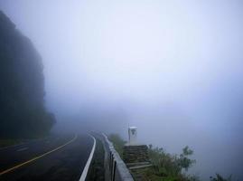 Asphalt road with yellow line at the top of the mountain in the morning mist photo