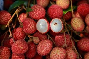 lichi, lichi fresco y pelado que muestra la piel roja y la pulpa blanca con hoja verde. foto