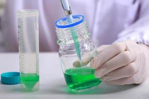Woman scientist biochemist at the workplace makes the analysis in the modern laboratory. She is holding a dropper and a test tube photo