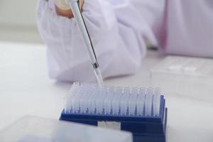 Woman scientist biochemist at the workplace makes the analysis in the modern laboratory. She is holding a dropper and a test tube photo