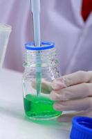 Woman scientist biochemist at the workplace makes the analysis in the modern laboratory. She is holding a dropper and a test tube photo