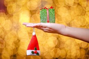 Merry Christmas and Happy New Year. Gift Christmas in woman's hands with glowing hearts bokeh. photo