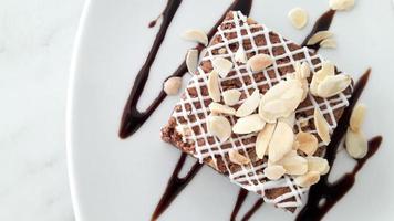 Top view of chocolate brownie with sliced almond on white plate background photo