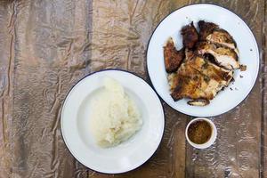 pollo a la parrilla y arroz pegajoso sobre fondo de madera foto