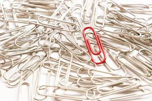 Red paper clip show different from the others on white background photo