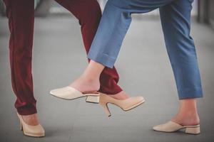 Foot tap. New novel greeting to avoid the spread of corona virus. Two women friends meet  Instead of greeting with a hug or handshake, they touch their feet together instead. photo