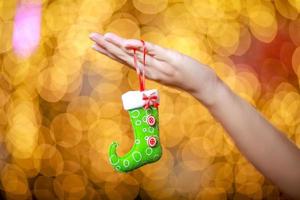 Merry Christmas and Happy New Year. Gift Christmas in woman's hands with glowing hearts bokeh. photo