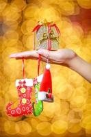 Merry Christmas and Happy New Year. Gift Christmas in woman's hands with glowing hearts bokeh. photo