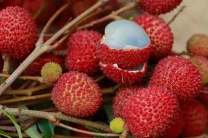 Lychee, Fresh lychee and peeled showing the red skin and white flesh with green leaf . photo