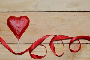 Chocolate heart wrapped in red and Red Ribbon on wood. valentine concept. Space for text. photo